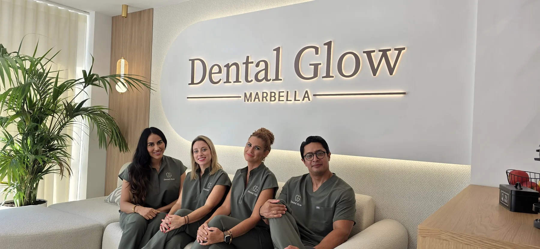 Equipo de Dental Glow en la sala de espera junto al logotipo de la clínica en Marbella